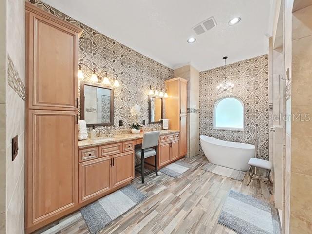 bathroom with tile walls, vanity, wood-type flooring, and plus walk in shower