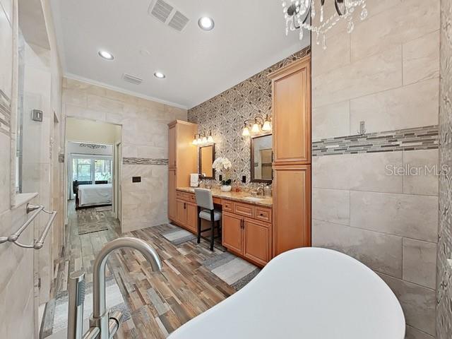 bathroom featuring crown molding, tile walls, a bathtub, vanity, and wood-type flooring