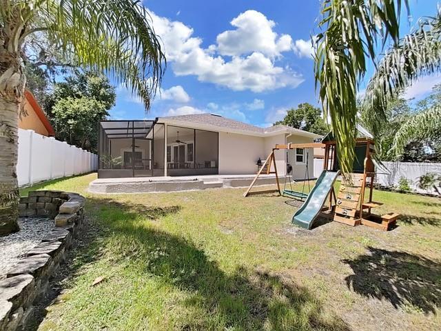 rear view of property with a playground, a lanai, and a lawn