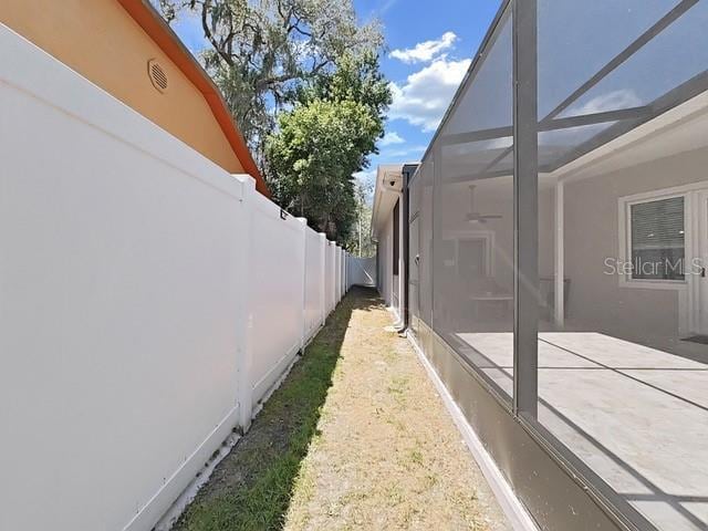 view of side of property featuring glass enclosure and a patio