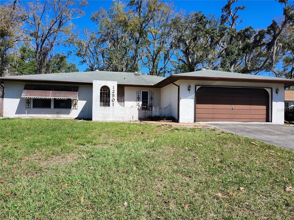 12501 Shadow Ridge Blvd, Hudson, FL 34669 - ranch-style home featuring driveway, a garage, a front lawn, and stucco siding