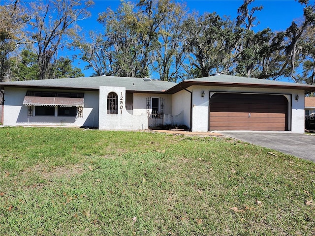 ranch-style home featuring driveway, a garage, a front lawn, and stucco siding