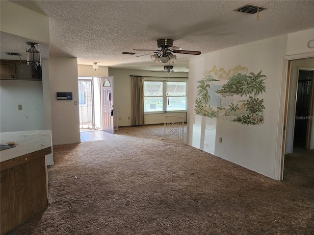 spare room with a ceiling fan, carpet flooring, visible vents, and a textured ceiling