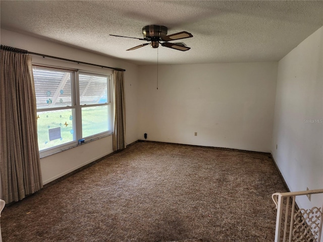 carpeted spare room featuring a textured ceiling, a ceiling fan, and baseboards