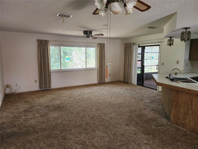 unfurnished living room with plenty of natural light, light carpet, a sink, and visible vents