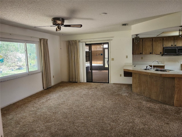 kitchen featuring carpet floors, a textured ceiling, black microwave, and a sink