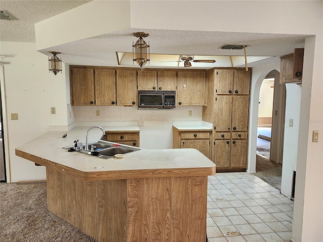 kitchen with arched walkways, visible vents, a sink, black microwave, and a peninsula