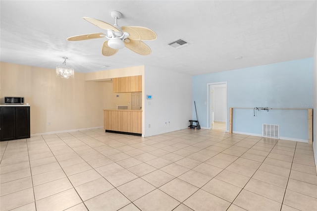 unfurnished living room featuring light tile patterned flooring and ceiling fan with notable chandelier