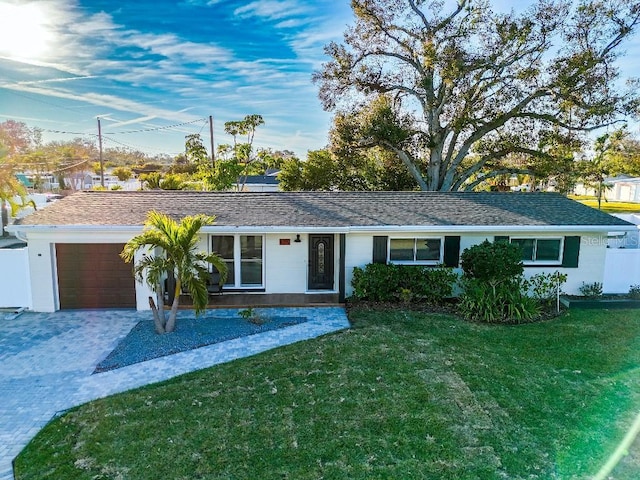 ranch-style home with a garage and a front lawn