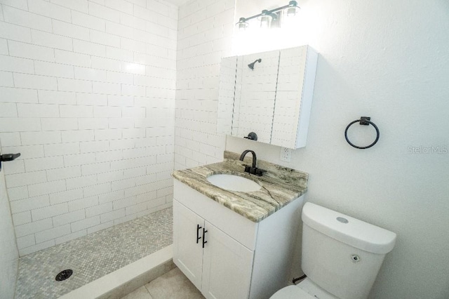 bathroom featuring vanity, a tile shower, and toilet