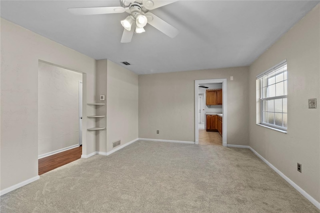 unfurnished bedroom featuring ensuite bath, light colored carpet, and ceiling fan