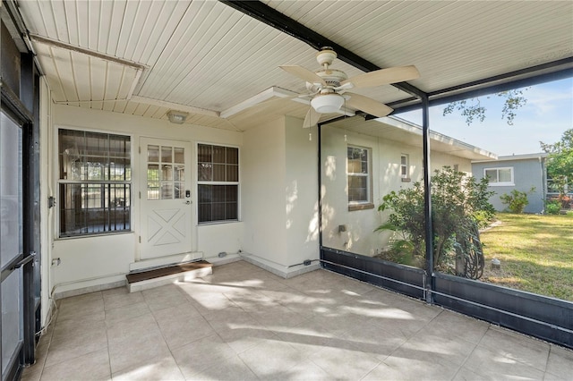 unfurnished sunroom featuring ceiling fan and plenty of natural light