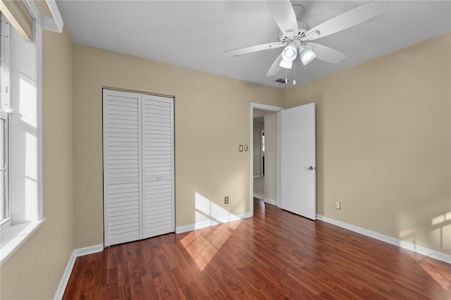 unfurnished bedroom with dark hardwood / wood-style floors, ceiling fan, and a closet