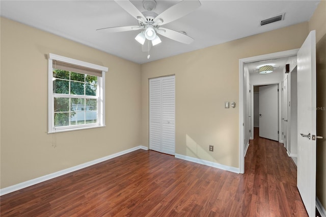 unfurnished bedroom with ceiling fan, dark hardwood / wood-style floors, and a closet