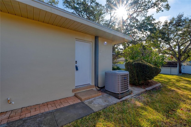 property entrance featuring cooling unit and a lawn