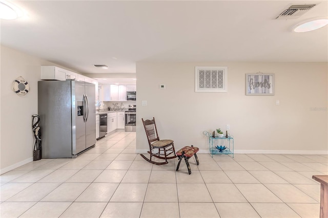 kitchen with stainless steel appliances, white cabinetry, sink, and light tile patterned floors