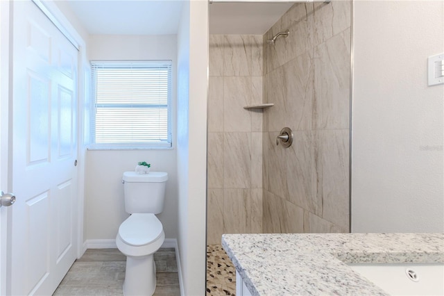 bathroom featuring vanity, wood-type flooring, toilet, and tiled shower