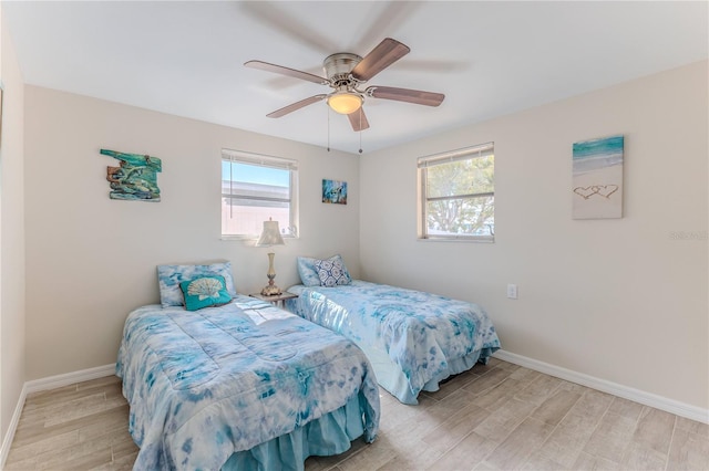 bedroom featuring ceiling fan, multiple windows, and light wood-type flooring