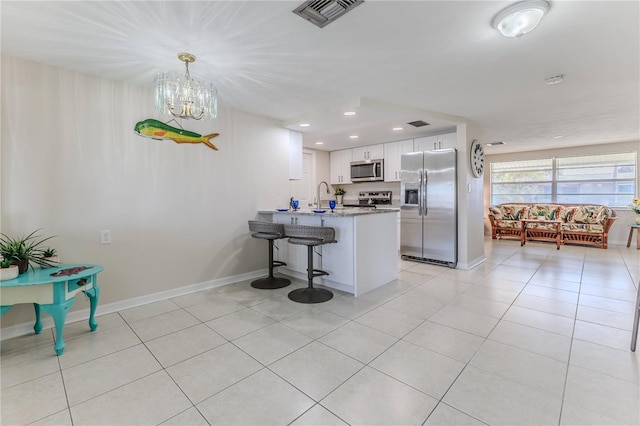 kitchen with a kitchen bar, sink, appliances with stainless steel finishes, white cabinetry, and kitchen peninsula