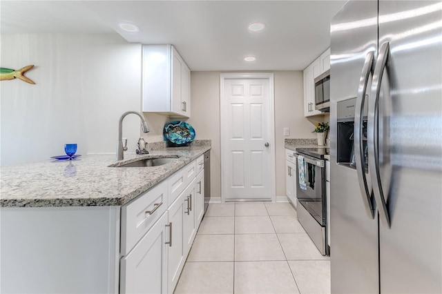 kitchen with stainless steel appliances, light stone counters, white cabinets, light tile patterned floors, and sink