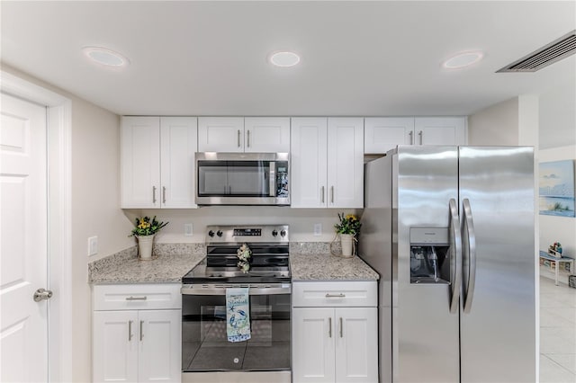 kitchen featuring white cabinets, appliances with stainless steel finishes, light stone counters, and light tile patterned floors