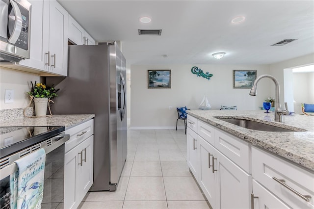 kitchen featuring white cabinetry, sink, light stone counters, appliances with stainless steel finishes, and light tile patterned flooring