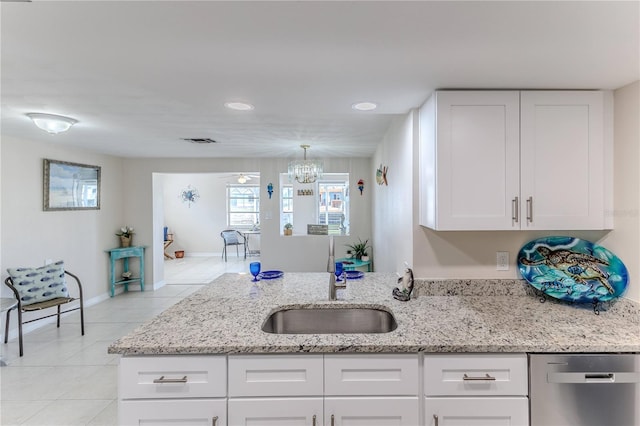 kitchen with sink, light stone counters, light tile patterned flooring, white cabinetry, and dishwasher