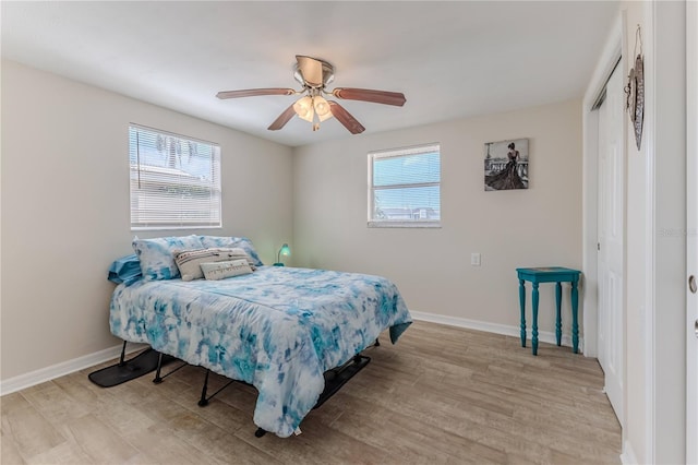 bedroom featuring light wood-type flooring, multiple windows, and a closet