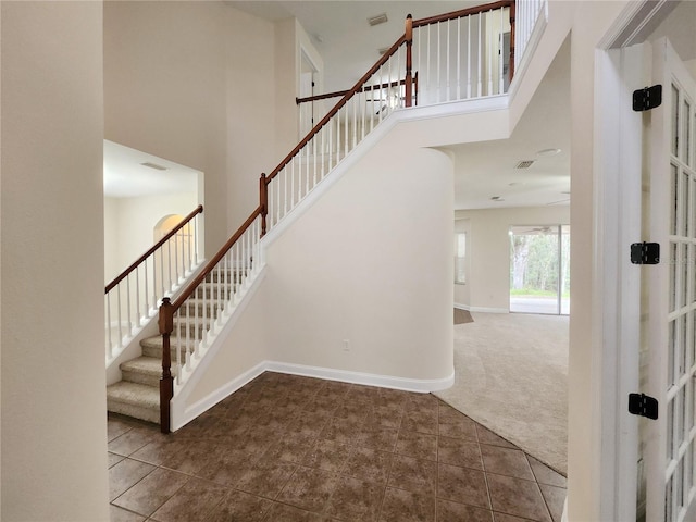 staircase with carpet floors and a towering ceiling