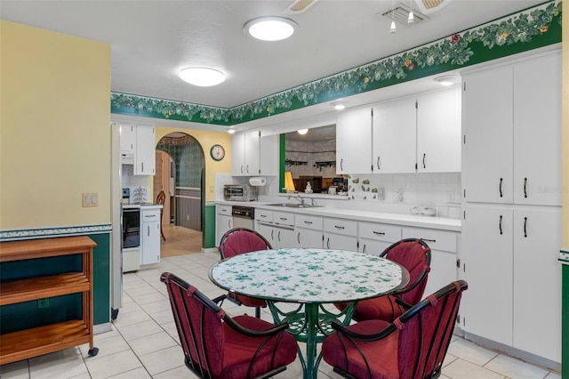 kitchen with sink, white cabinets, white dishwasher, and decorative backsplash