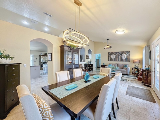 tiled dining space featuring lofted ceiling and a textured ceiling