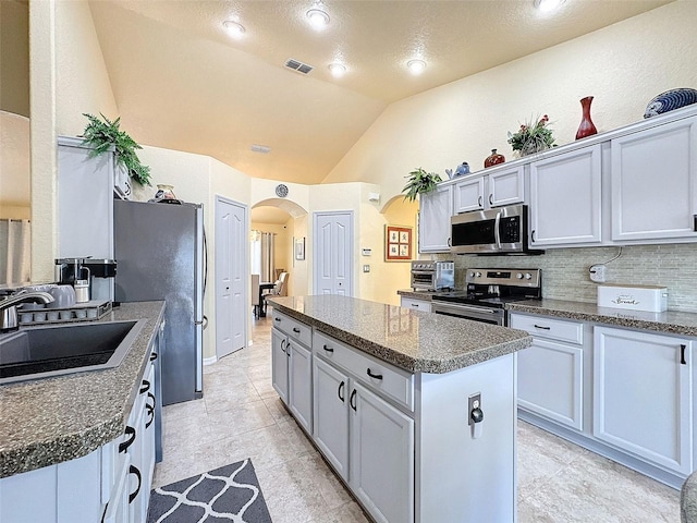 kitchen with tasteful backsplash, lofted ceiling, sink, a center island, and stainless steel appliances