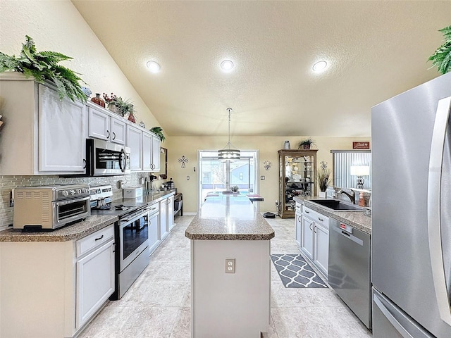 kitchen featuring hanging light fixtures, stainless steel appliances, white cabinets, and a kitchen island