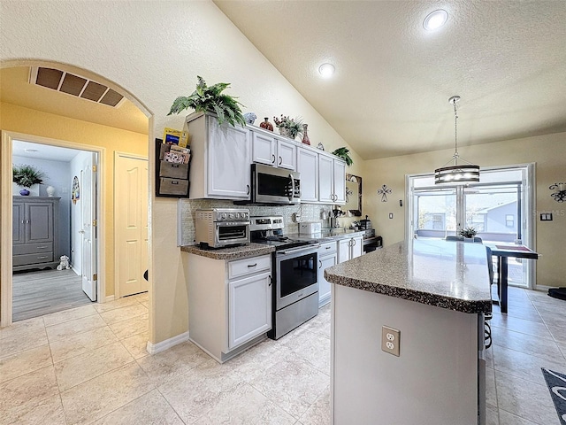 kitchen with pendant lighting, lofted ceiling, white cabinets, backsplash, and stainless steel appliances