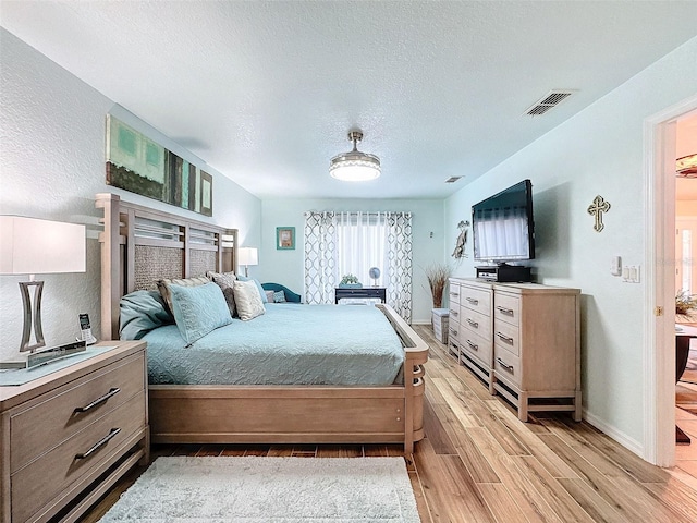 bedroom featuring a textured ceiling and light hardwood / wood-style floors