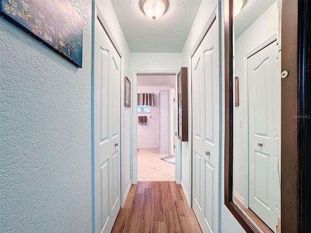 corridor featuring light hardwood / wood-style flooring and a textured ceiling