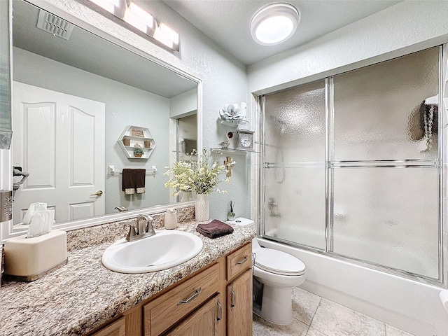 full bathroom with vanity, bath / shower combo with glass door, tile patterned floors, and toilet