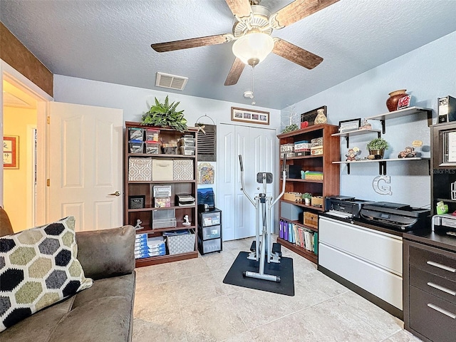 tiled office space featuring ceiling fan and a textured ceiling