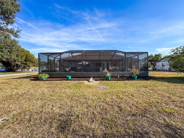 rear view of house with glass enclosure and a lawn