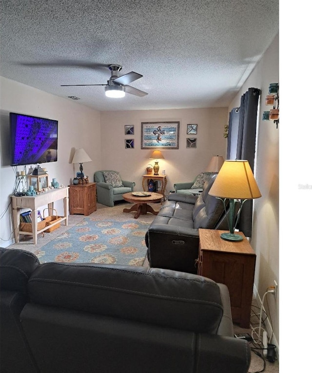 carpeted living room with ceiling fan and a textured ceiling