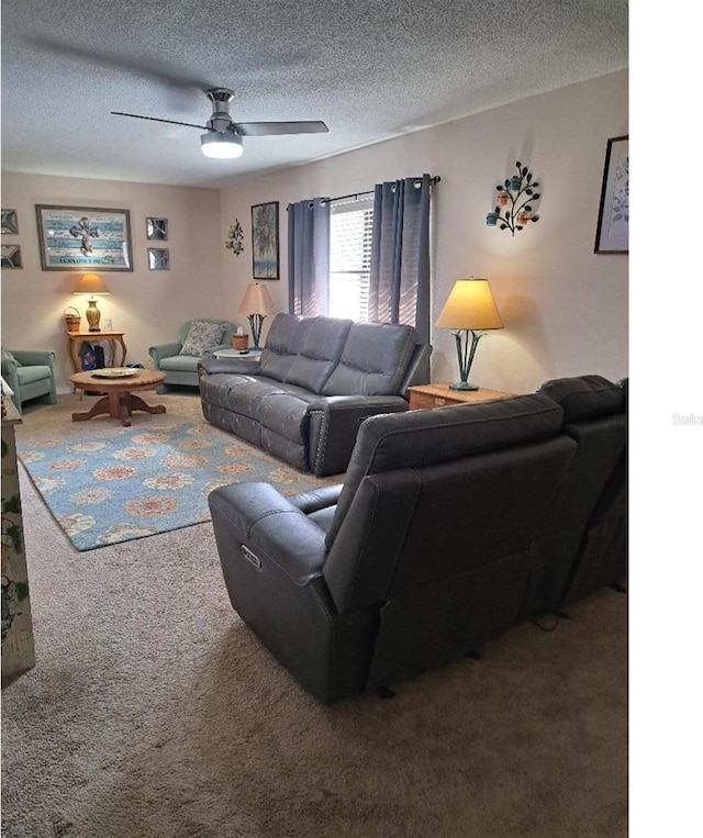 living room featuring ceiling fan, carpet floors, and a textured ceiling