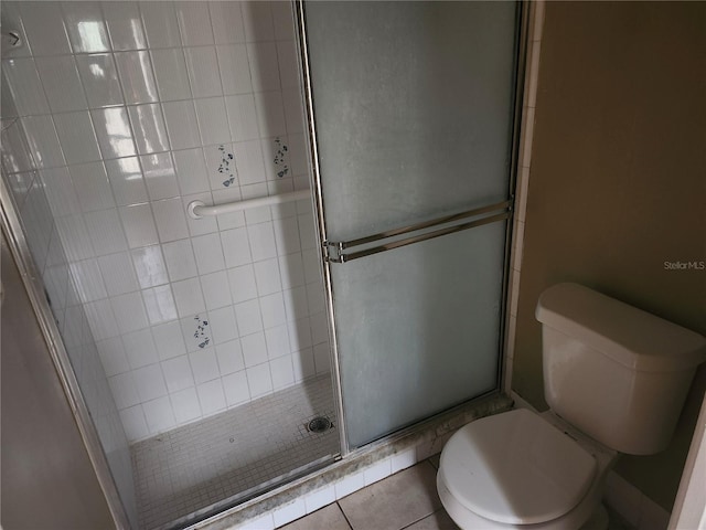 bathroom featuring tile patterned flooring, a shower with door, and toilet