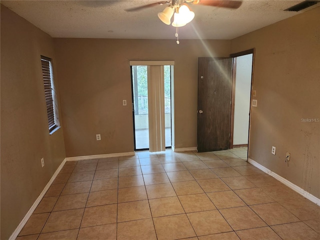 spare room featuring ceiling fan, light tile patterned floors, and a textured ceiling