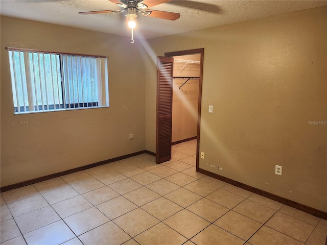 spare room featuring ceiling fan, light tile patterned flooring, and a textured ceiling