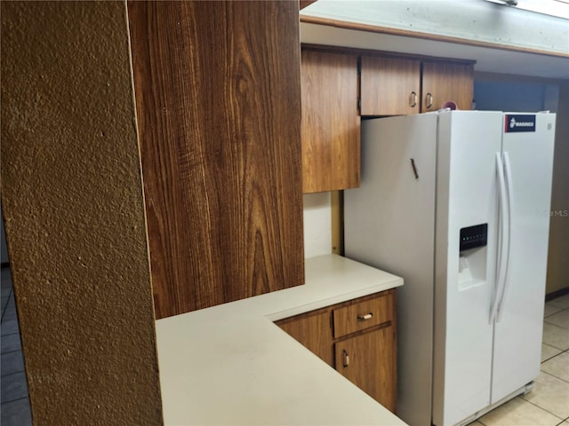 kitchen featuring light tile patterned floors and white refrigerator with ice dispenser