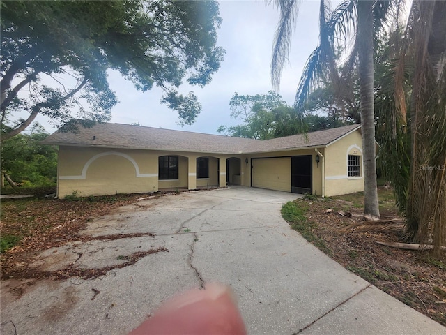 ranch-style house with stucco siding, driveway, and a garage
