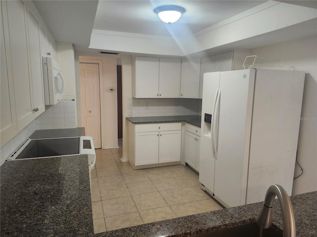 kitchen with white appliances, light tile patterned floors, white cabinetry, a tray ceiling, and backsplash