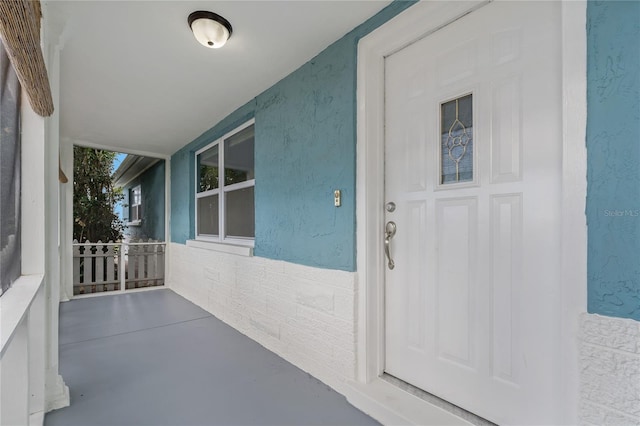 view of exterior entry featuring covered porch and stucco siding
