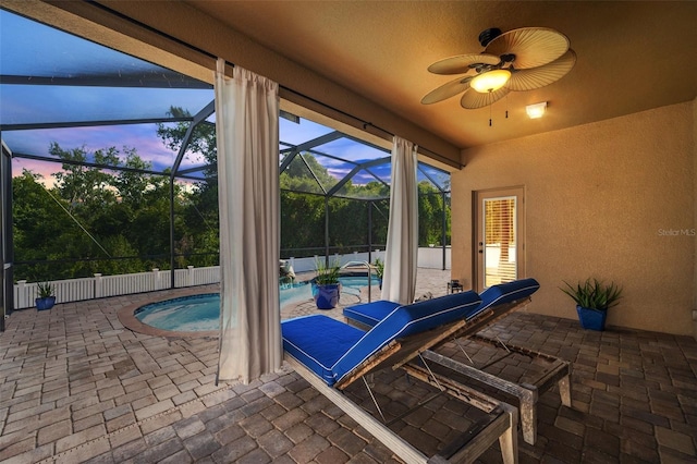 patio terrace at dusk featuring ceiling fan, a lanai, and a fenced in pool