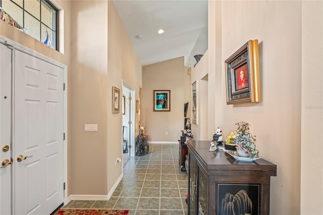 foyer featuring dark tile patterned floors and lofted ceiling